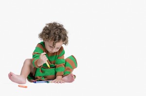 A toddler is hard at work with his crayons on the floor.