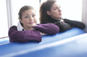 Two pretty high school students, riding the bus. 