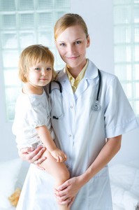 A nurse holds a young child on her hip.
