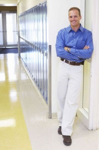 Photo of a male teacher, leaning up against the school lockers.