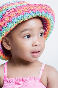 A young girl with a colorful hat on. Una joven con sombrero de muchos colores.