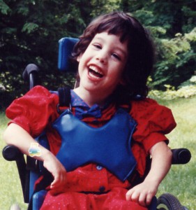 Picture of a laughing preschoolers in a wheelchair.