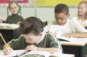 Scene of a classroom, students hard at work in their textbooks.