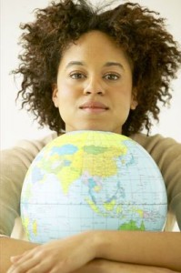 Photo of a young black woman, her chin resting on a globe.