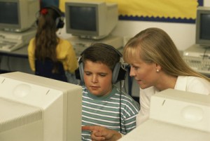 Picture of a special educator helping an elementary-school boy at a computer.