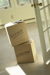 Foto de 2 cajas de mudanza en una puerta vacía, etiquetadas como "cocina" y "sala de estar"."