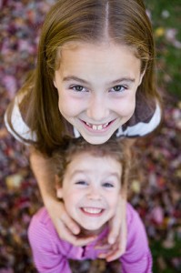 Closeup of the impish faces of two sisters.