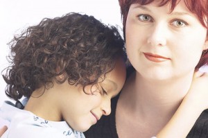 Mom looks seriously at you, with her daughter's head nustled in her shoulder. La mamá y su hija.