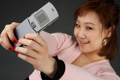 Photo of an Asian woman with her cell phone held high.