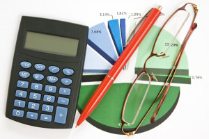 Photo of a calculator, pen, statistics graph, and eyeglasses