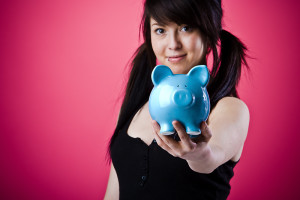 Young woman holding a piggy bank out to you