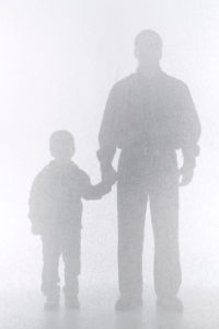 Shadowy figures of a father holding a young boy's hand