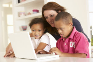 Teacher works with young boy with Down syndrome and another child