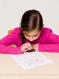 Young girl with her head bent over the test she's taking