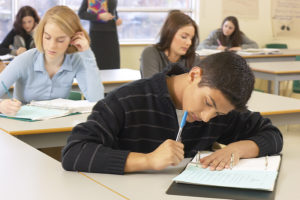 Teen student with his head bent over his schoolwork.