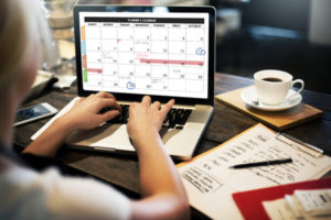 Woman typing on computer screen showing calendar