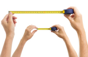 Two sets of hands hold up a measuring tape drawn to different lengths
