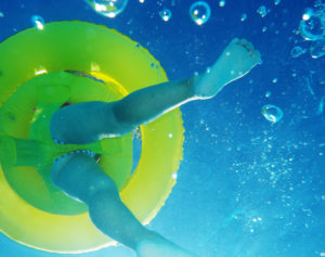 Underwater view of legs and a bright yellow water chair, obviously a child in the pool