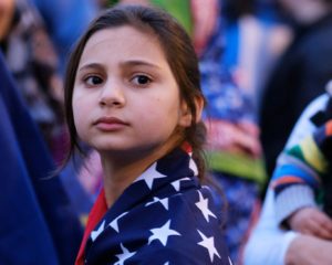 Young immigrant girl, wrapped in a US flag