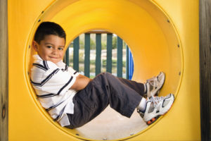 Young boy lying in crawl tube at playground