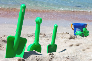 3 green beach shovels and a blue beach bucket