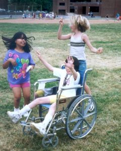 3 girls dancing outside, one in a wheelchair