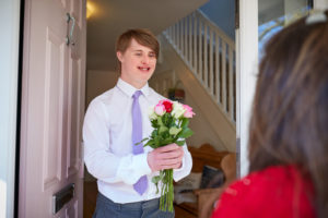 Young man with Down Syndrome brings flowers to his date