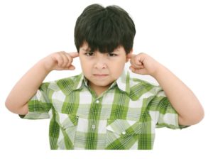 Photo of a boy with his fingers in his ears and an obstinate look on his face