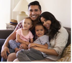 Hispanic family cuddled together on sofa, dad, mom, and 2 children