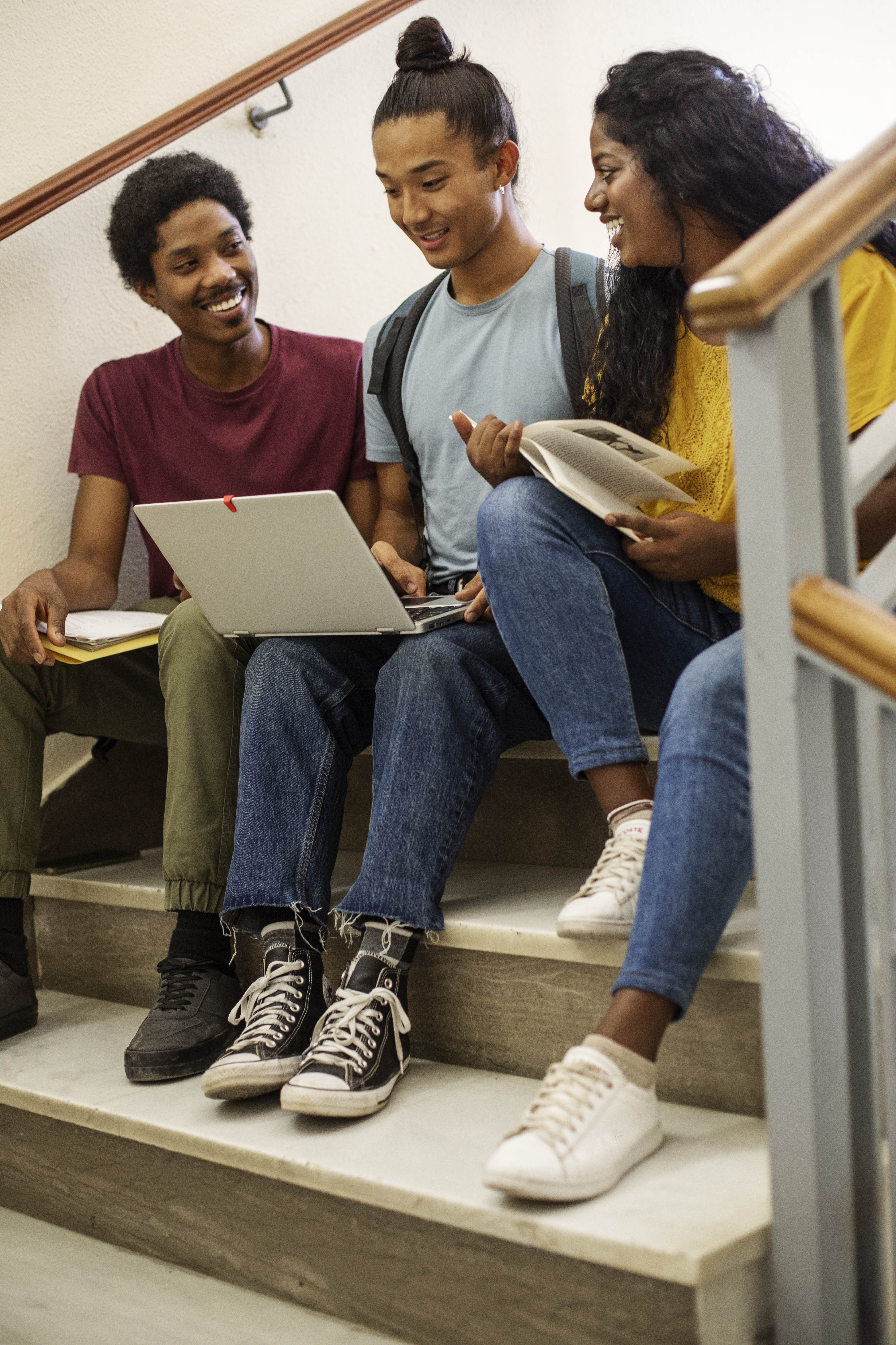 -students-different-ethnicities-cramming high school teens sitting on steps in high school hallway