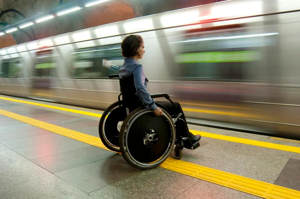 person in wheelchair in subway platform waiting for train