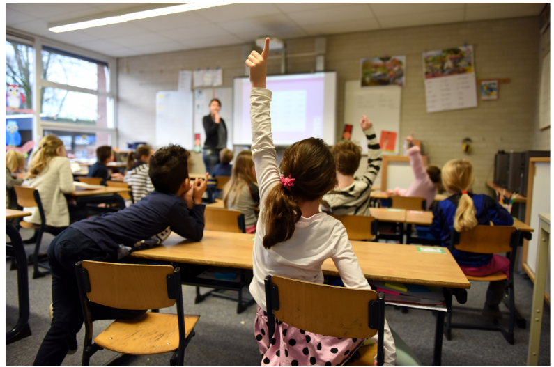 Students in classroom Students in classroom raising their hands.