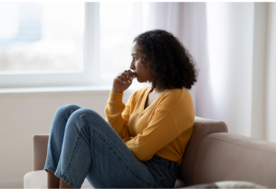 Sadyoungwoman Young woman sitting on sofa looking sadly into the distance.