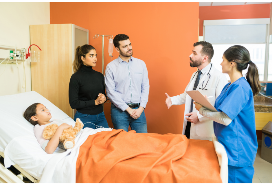 ER Care Little girl in hospital bed with family and doctor standing around her bed talking.