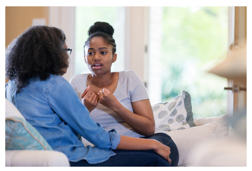 Picture of two women speaking with one holding her hands up as if trying to make a point. 