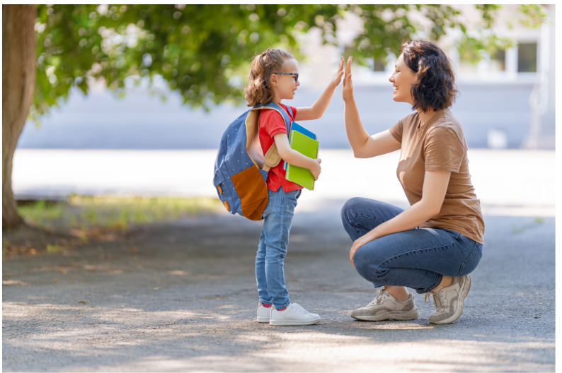 Mom giving daughter going to school a high five.