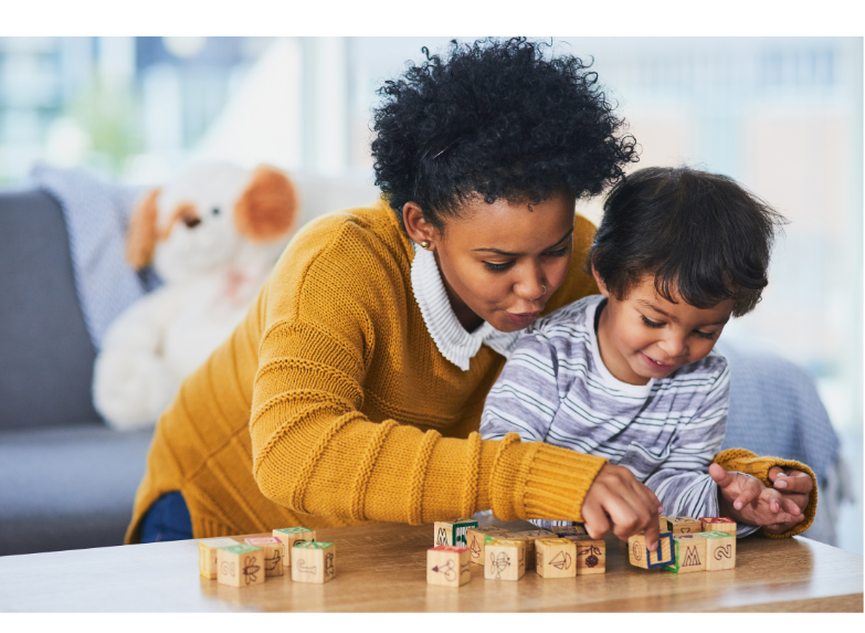 Teacher reaching over student and playing with blocks.