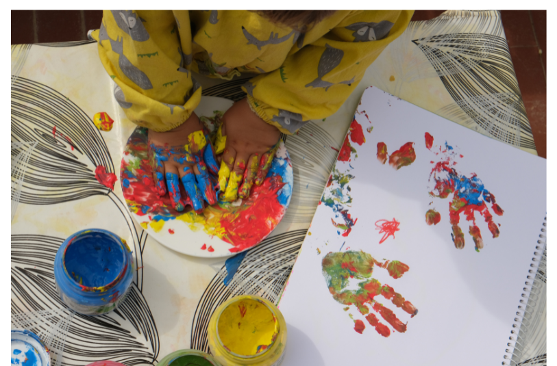 Child making hand prints with paint and their hands. 