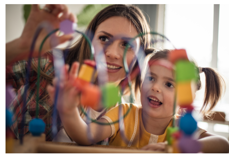 Teacher and little girl playing with a child's toy. 
