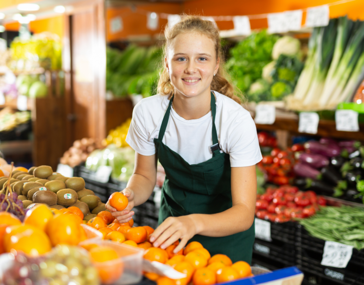 Young woman smiling among a fruit stand.
